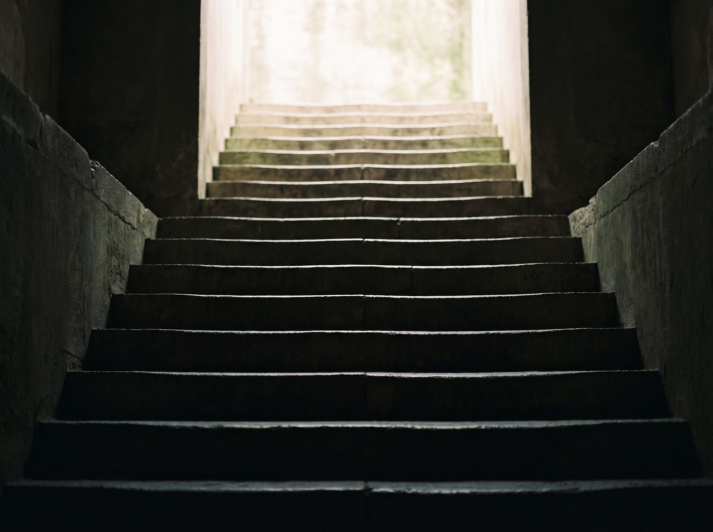 A stone staircase rising from shadow toward bright daylight